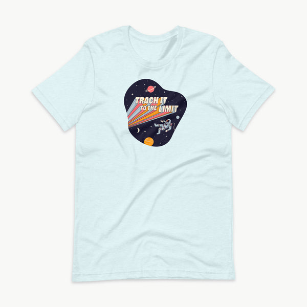 An illustration of an astronaut with a trach and tubing floating in outer space surrounded by stars and planets. Behind the astronaut, bold retro text reads “Trach It to the Limit,” with colorful light trails shooting from the words like a rocket launch. The design appears on a dark background. It is on a heather ice blue adult t-shirt.