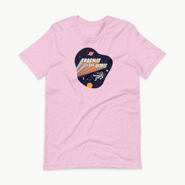 An illustration of an astronaut with a trach and tubing floating in outer space surrounded by stars and planets. Behind the astronaut, bold retro text reads “Trach It to the Limit,” with colorful light trails shooting from the words like a rocket launch. The design appears on a dark background. It is on a heather prism lilac adult t-shirt.