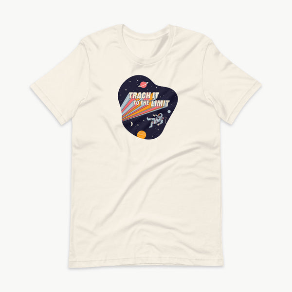 An illustration of an astronaut with a trach and tubing floating in outer space surrounded by stars and planets. Behind the astronaut, bold retro text reads “Trach It to the Limit,” with colorful light trails shooting from the words like a rocket launch. The design appears on a dark background. It is on a vintage white adult t-shirt.