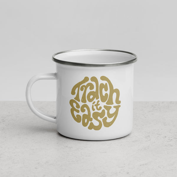 A white enamel mug with a white coating and silver rim with the text "Trach it Easy" in gold hand lettering on the side.